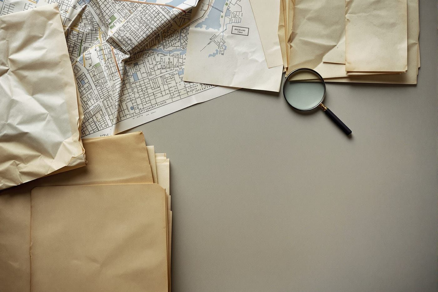 Archival documents, folded street maps and printed ephemera spread on a table